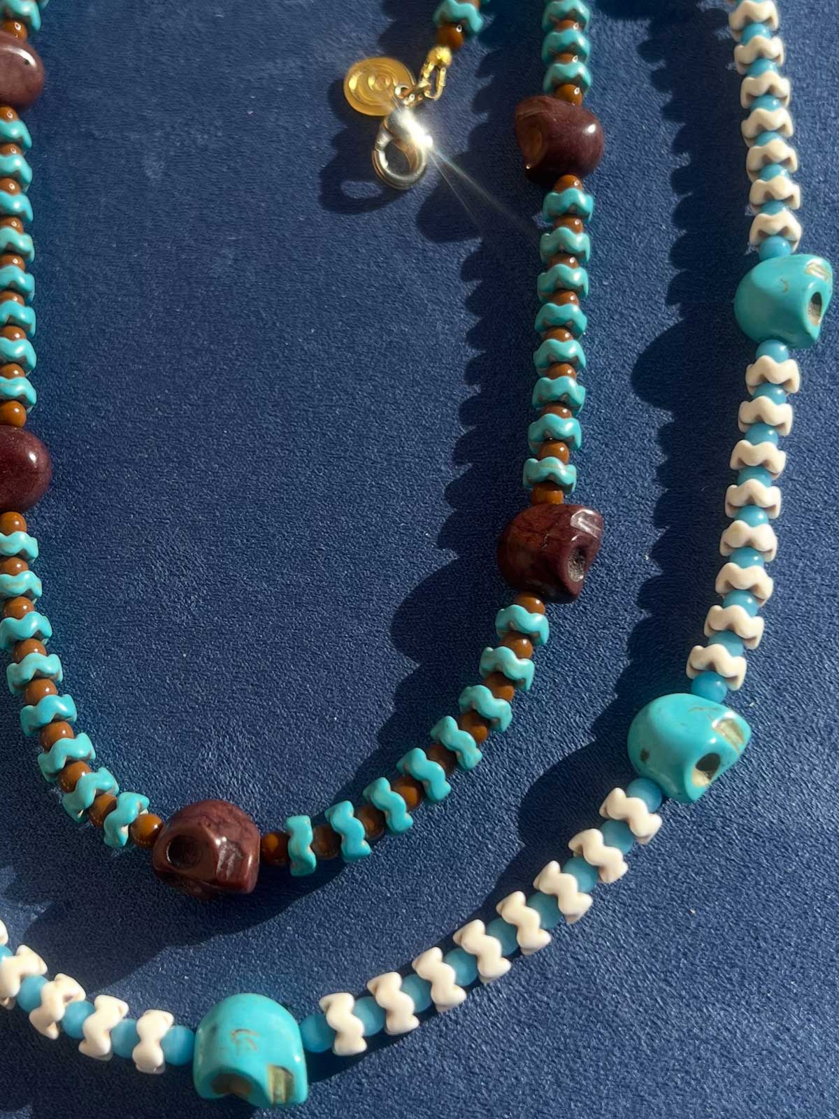 Skull charm beaded necklaces made with howlite gemstones in brown, turquoise and ivory.