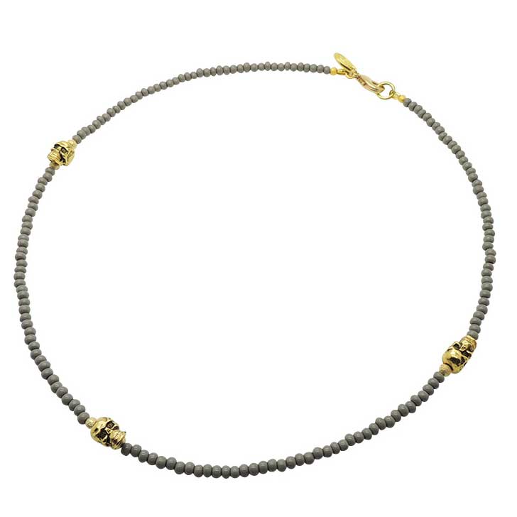 A men's grey glass beaded necklace with three gold skull charms adorned with gold stardust beads. by Dana Levy