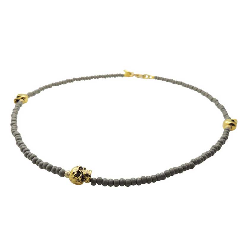 Grey glass beaded necklace with gold skull charms on a white background by Dana Levy