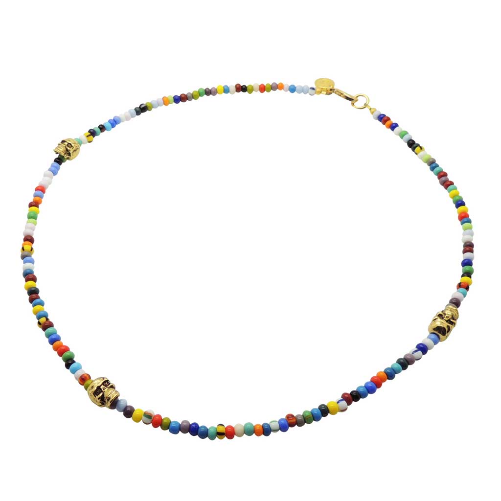 A multicolour glass bead necklace with three gold plated skull charms and clasp on white background by Dana Levy