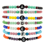 A Stack of Dana Levy Initial Letter Charm Glass Bead Mix Bracelets with the Letters A to G in a Variety of Colours.