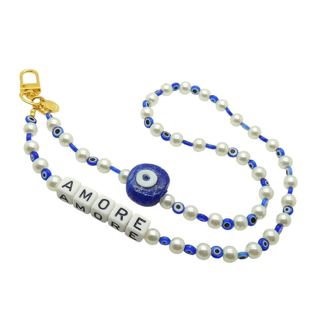 Dana Levy Faux pearl phone strap with royal blue evil eye glass beads and 'AMORE' cube beads and gold plated clip on a white background.