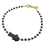 Dana Levy dark brown bone fish charm striped glass bead mix anklet with ivory glass beads and black/white striped glass beads and a gold plated clasp on a white background.
