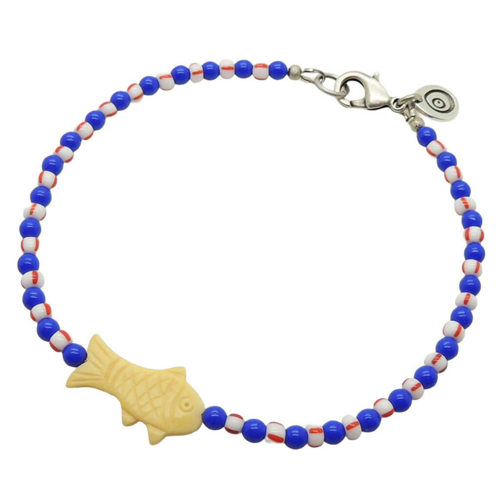 Dana Levy cream bone fish charm striped glass bead mix anklet with royal blue glass beads and white/red striped glass beads and an antique silver plated clasp on a white background. 