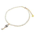 A Dana Levy freshwater pearl choker with a diamante evil eye shaped charm pendant, with a dangling pearl, on a white background. 