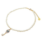 A Dana Levy freshwater pearl choker with a diamante evil eye shaped charm pendant, with a dangling pearl, on a white background. 