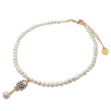 A Dana Levy white freshwater pearl necklace with a gold-tone clasp and extender chain, featuring an evil eye hamsa hand shaped charm with a dangling pearl bead, on a white background.