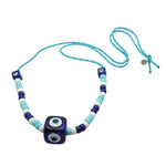 Dana Levy royal blue evil eye cube charms and turquoise white and navy glass beads on a turquoise nautical cord necklace on a white background. 