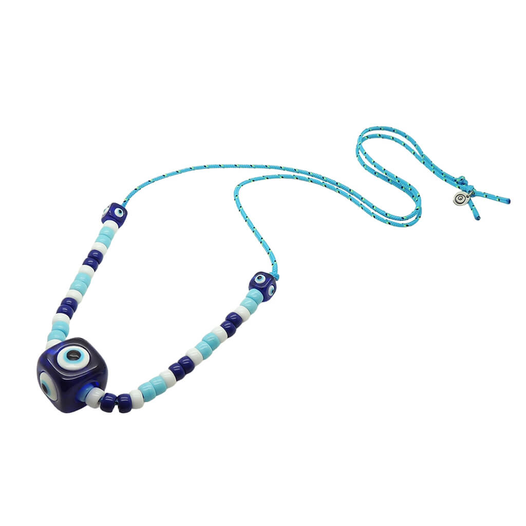 Dana Levy royal blue evil eye cube and turquoise white and navy glass beads on a turquoise cord necklace on a white background. 
