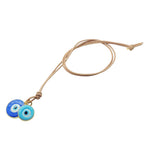 Dana Levy evil eye disc duo leather cord necklace with large blue and small turquoise evil eyes on natural leather cord on a white background. 