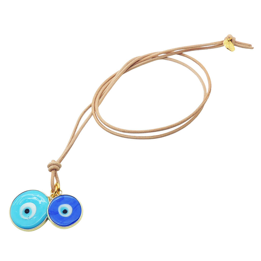 Dana Levy evil eye disc duo leather cord necklace with large turquoise and small blue evil eyes on natural leather cord on a white background. 
