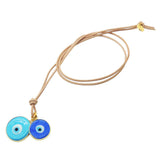 Dana Levy evil eye disc duo leather cord necklace with large turquoise and small blue evil eyes on natural leather cord on a white background. 