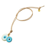 Dana Levy evil eye disc duo leather cord necklace with large white and small turquoise evil eye disc charms on natural leather cord on a white background. 