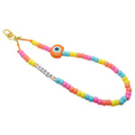 Dana Levy bright candy coloured personalised name saying Hodge phone charm strap with an orange evil eye charm on a white background. 