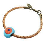 Dana Levy braided tan leather bracelet with an antique bronze clasp and a round turquoise bead featuring an orange and blue centre, shown on a plain white background.