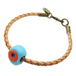 Dana Levy natural tan leather braid bracelet with an opaque turquoise and orange glass evil eye amulet, shown on a plain white background.