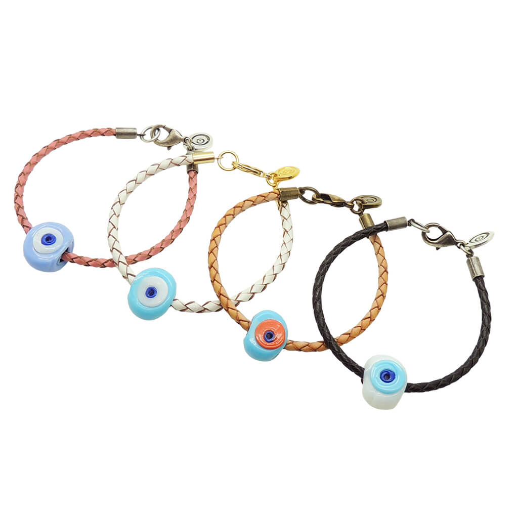 Dana Levy four braided leather cord bracelets with chunky glass evil eye charms, arranged diagonally on a white background. The cords are pink, white, tan, and black, with various plated clasps.