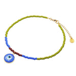 A Dana Levy glass beaded choker with olive, blue and brown beads, featuring a round blue evil eye pendant charm and a gold plated chain extender clasp on a plain white background.