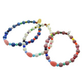 Dana Levy trio of pink heart charm gemstone bracelets in lapis lazuli, mother of pearl and rhodonite with rainbow glass beads on a white background. 