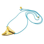 Dana Levy gold plated large shark tooth amulet on a turquoise nautical cord necklace on a white background. 