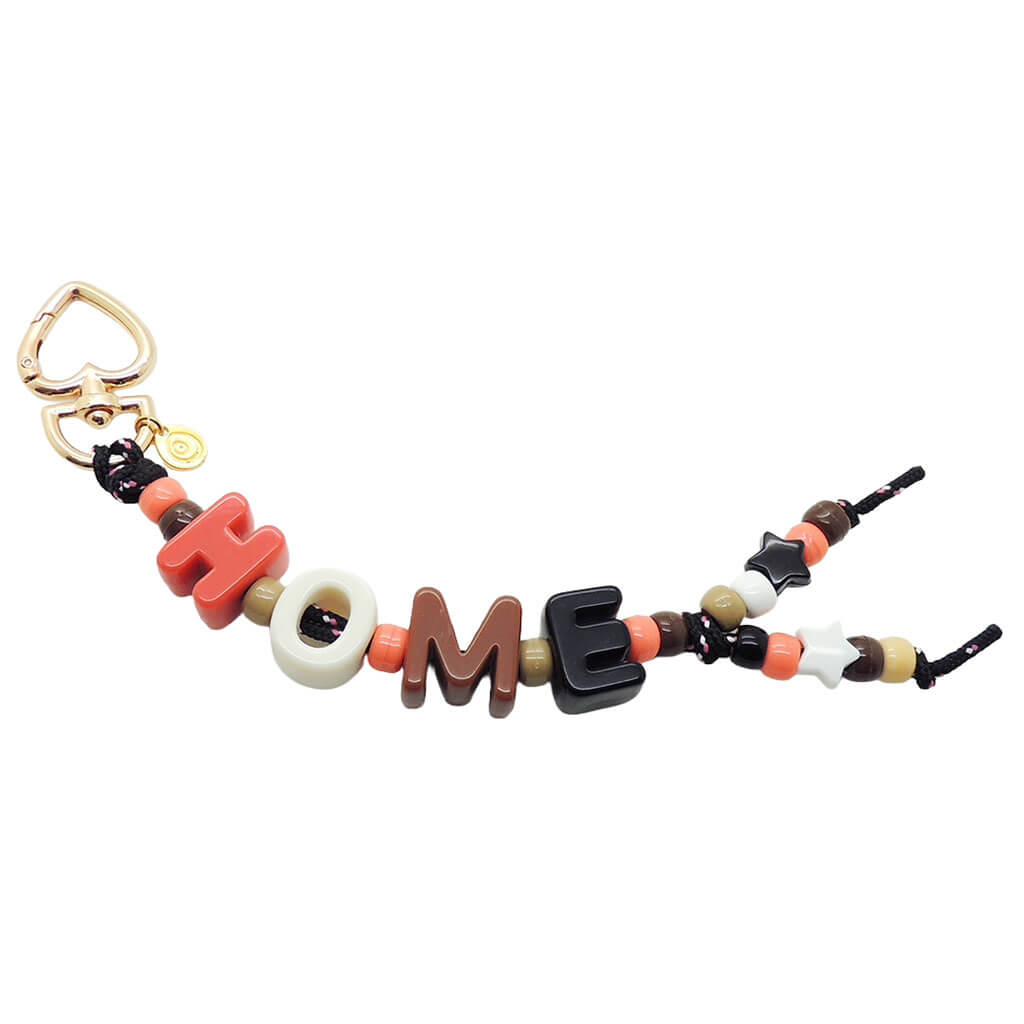 A Dana Levy maxi alphabet personalised name bag charm with HOME in large acrylic letters in neutral colours and charm beads on a white background. 