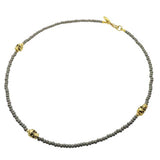 A men's grey glass beaded necklace with three gold skull charms adorned with gold stardust beads. by Dana Levy 