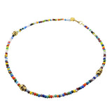 A multicolour glass bead necklace with three gold plated skull charms and clasp on white background by Dana Levy 