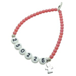 A Dana Levy dark rose newborn baby milestone glass bead bracelet with birth date in white acrylic letters and a silver plated mini girl icon charm, on a white background. 