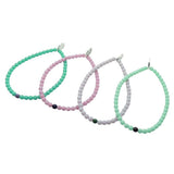 Dana Levy Set of four glass beaded bracelets in green, pink, grey, and light mint green on a white background