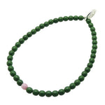 Dana Levy forest green glass beaded bracelet with a pink bead on a white background