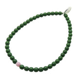 Dana Levy forest green glass beaded bracelet with a pink bead on a white background