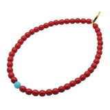 Dana Levy red glass beaded bracelet with a turquoise blue bead and gold clasp on a white background