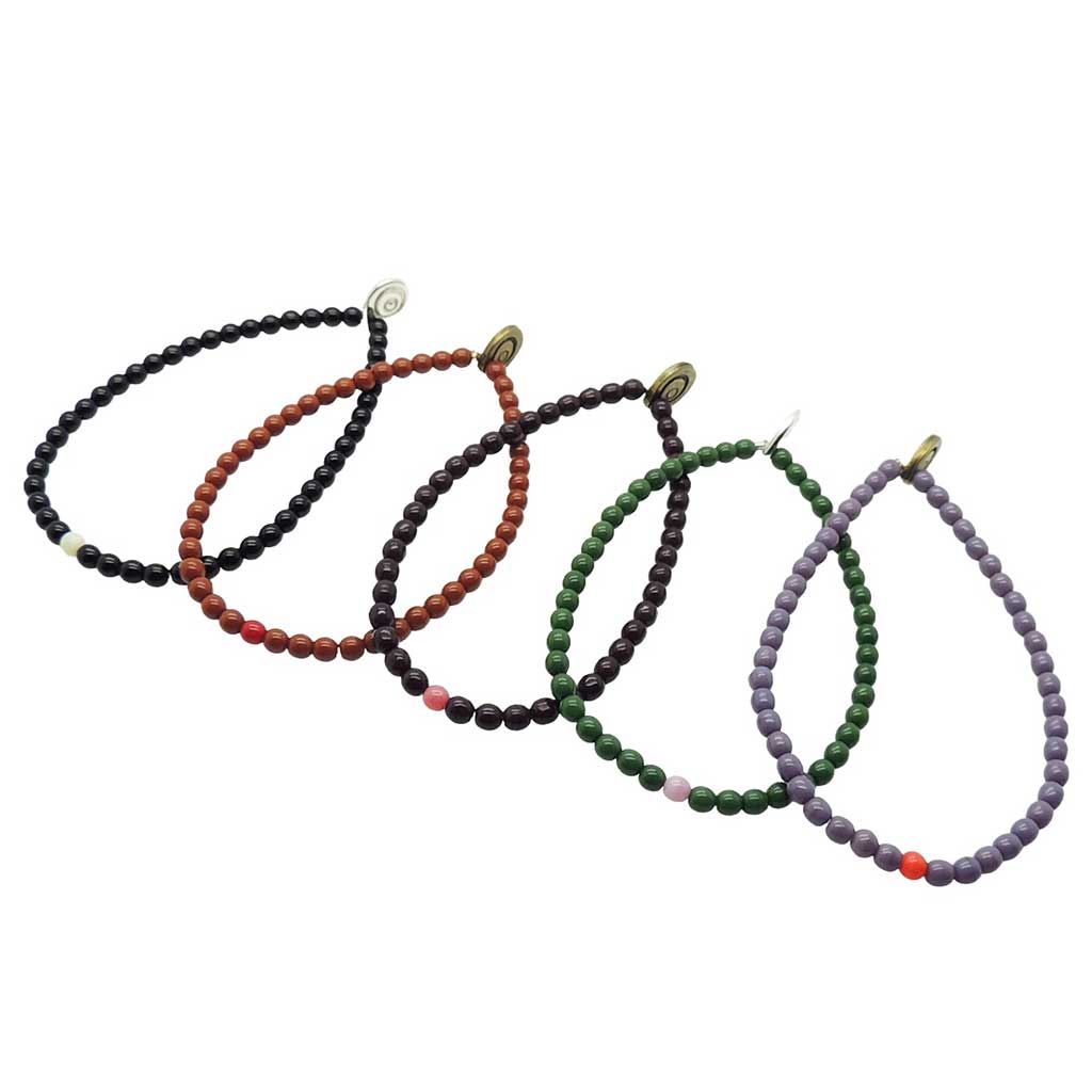 Set of five Dana Levy glass beaded bracelets in black, brown, maroon, green, and purple on a white background