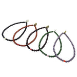 Set of five Dana Levy glass beaded bracelets in black, brown, maroon, green, and purple on a white background