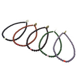 Set of five Dana Levy glass beaded bracelets in black, brown, maroon, green, and purple on a white background