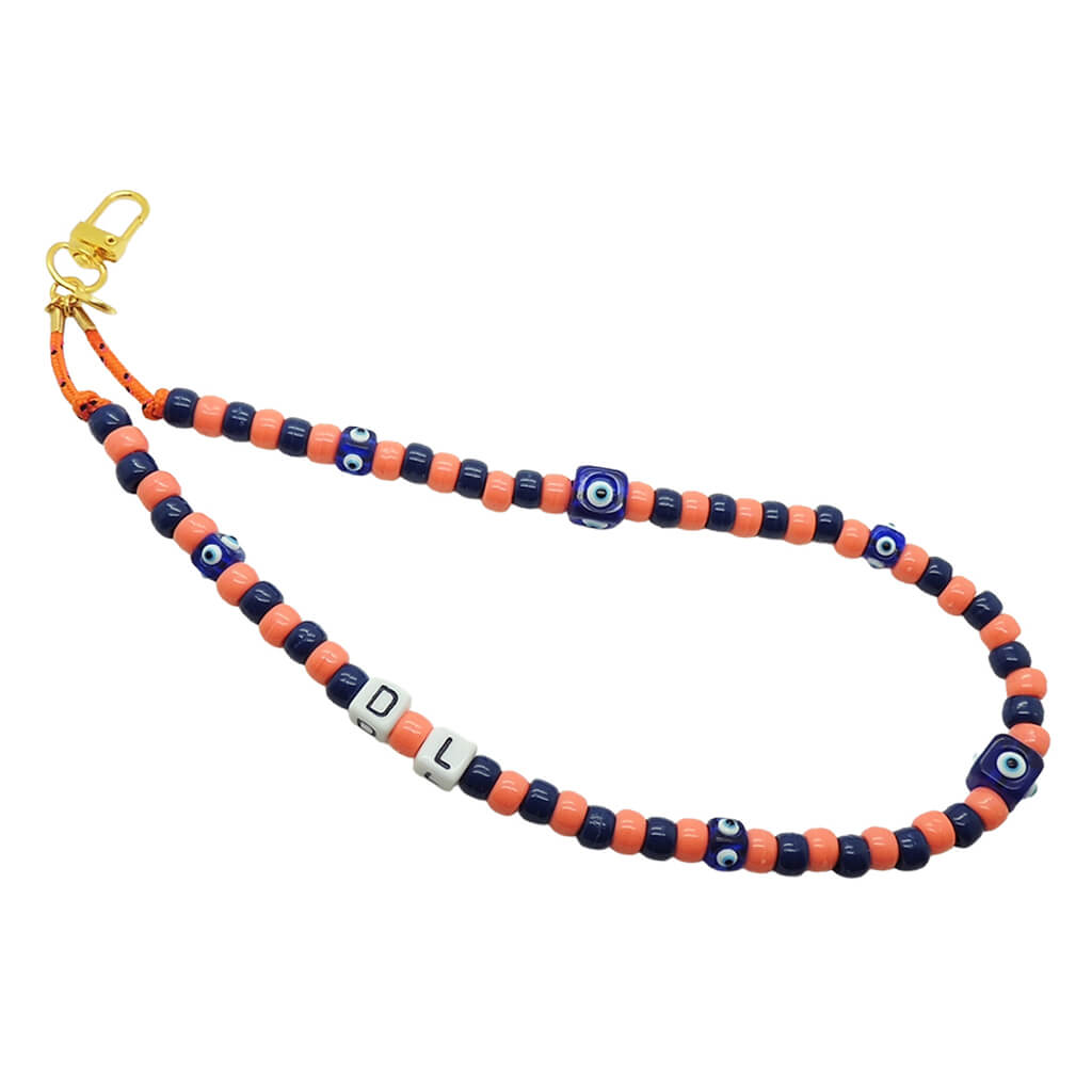 Dana Levy peach and navy beaded phone strap with blue evil eye cube charms and DL initial cubes on a white background. 