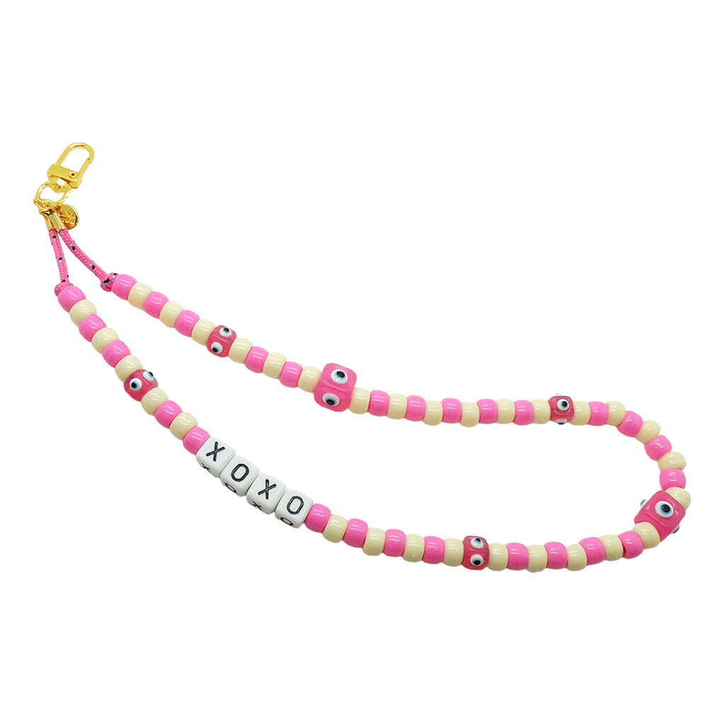 Dana Levy pink and cream beaded phone strap with 'XOXO' charm and pink evil eye cubes on a white background.
