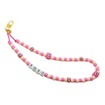 Dana Levy pink and cream beaded phone strap with 'XOXO' charm and pink evil eye cubes on a white background.