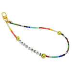 Dana Levy Rainbow coloured glass bead phone charm strap with 'HAPPINESS' and yellow smiley face charms on a white background