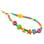 Dana Levy rainbow bright colourful acrylic beaded phone charm strap with alphabet letters that read gelato and a yellow smiley flower charm with a gold clasp on a white background.