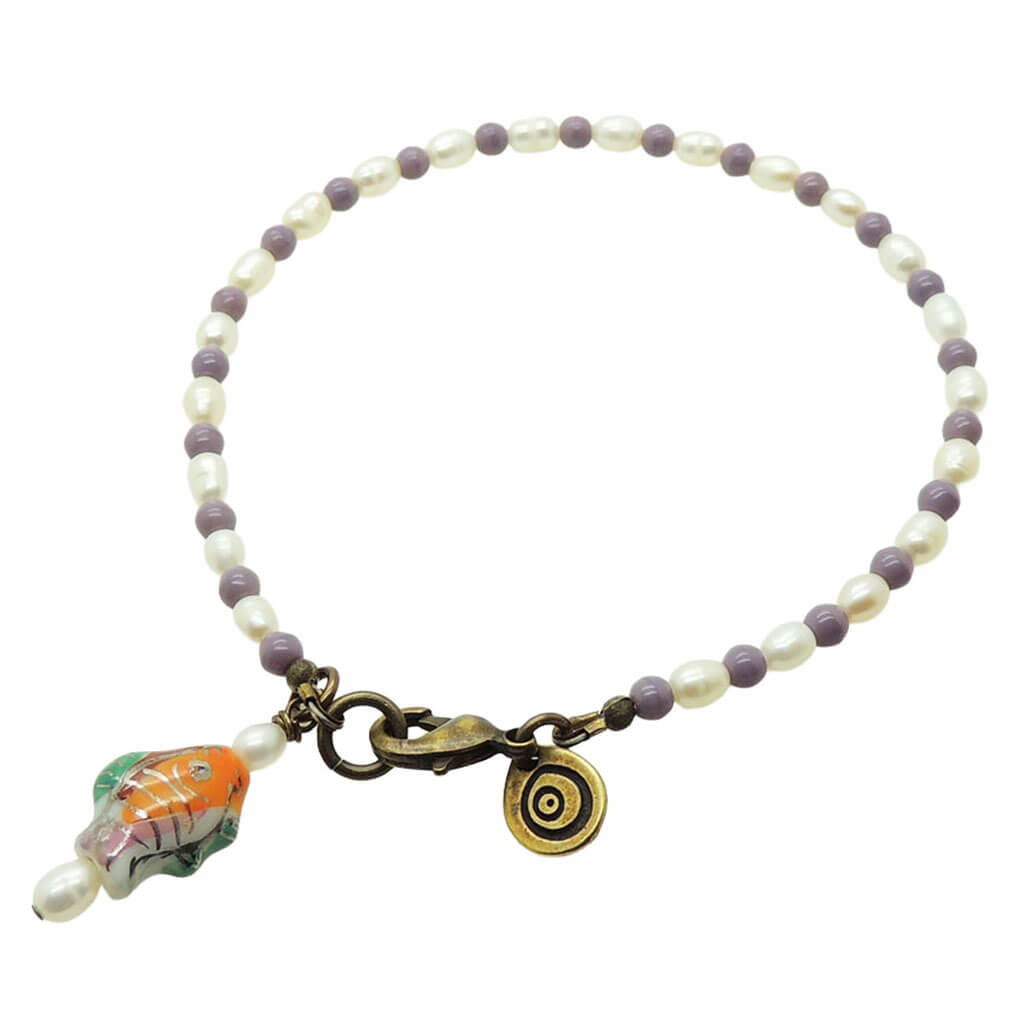 Dana Levy porcelain fish charm freshwater pearl glass bead mix anklet with purple glass beads and antique gold clasp on a white background. 