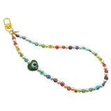 Dana Levy rainbow glass evil eye heart faux pearl beaded phone wristlet strap with a transparent green evil eye heart charm on a white background.