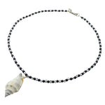 Dana Levy necklace with black and white stripe glass beads and a conch seashell pendant on a white background.