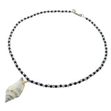Dana Levy necklace with black and white stripe glass beads and a conch seashell pendant on a white background.