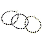 Dana Levy trio of grey, black and ivory striped glass beaded bracelets on a white background.