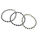 Dana Levy trio of grey, black and ivory striped glass beaded bracelets on a white background.