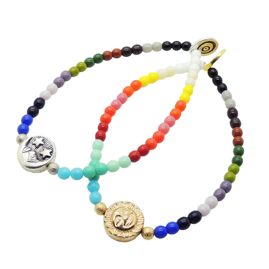 Dana Levy colourful rainbow beaded bracelets with a silver moon charm and a gold sun charm on a white background