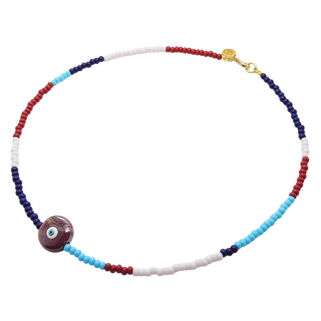 A Dana Levy beaded necklace with repeating segments of navy blue, light pink, turquoise, and red glass beads, featuring a large ceramic pearlised maroon evil eye charm and a gold clasp, shown on a plain white background.