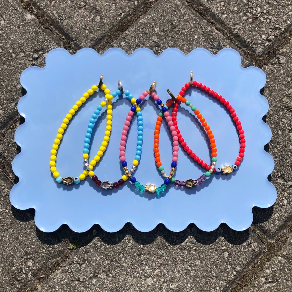 Dana Levy Solid Mini Hamsa Hand Charm Glass Bead Mix Bracelet - Group on Blue Flatlay 