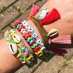 Dana Levy personalised name bracelet that reads luv you lots with friendship bracelets on a wrist at Glastonbury.